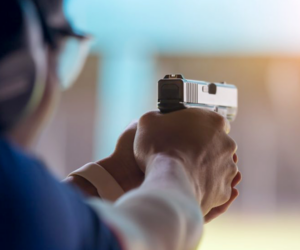 Man at a shooting range aiming a gun.